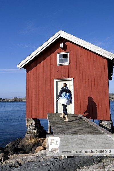 Eine Frau zu Fuß durch ein Bootshaus Bohuslan Schweden.