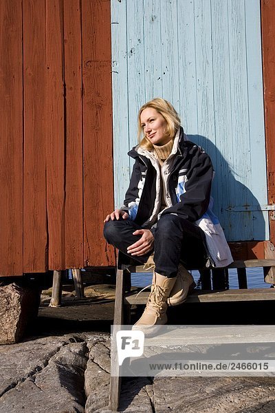 A woman sitting by a boathouse Bohuslan Sweden.