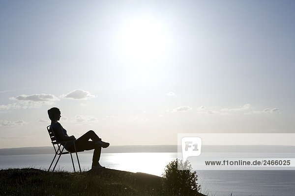 Eine Frau sitzen auf einem Stuhl Blick auf Vattern Schweden.