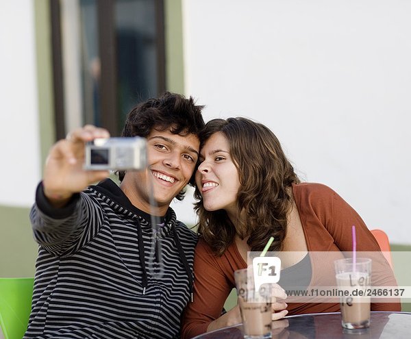 A young couple sitting at a caf holding a camera Portugal.