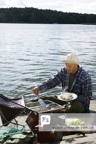A man barbecuing fish by the water Sweden.