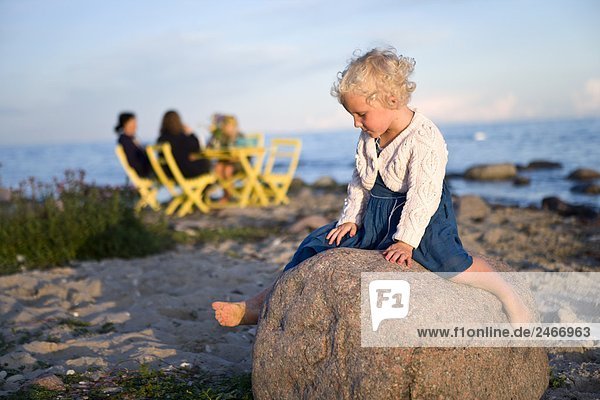 Ein Mädchen sitzt auf einem Rock Oland Schweden.