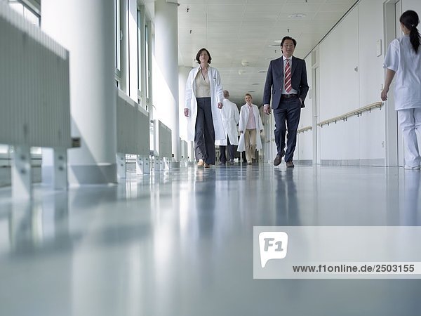 Ärzte und Geschäftsmann Wandern im Korridor Krankenhaus
