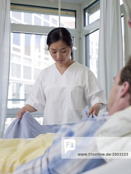 Female Nurse ändern Bettlaken des Patienten Bett