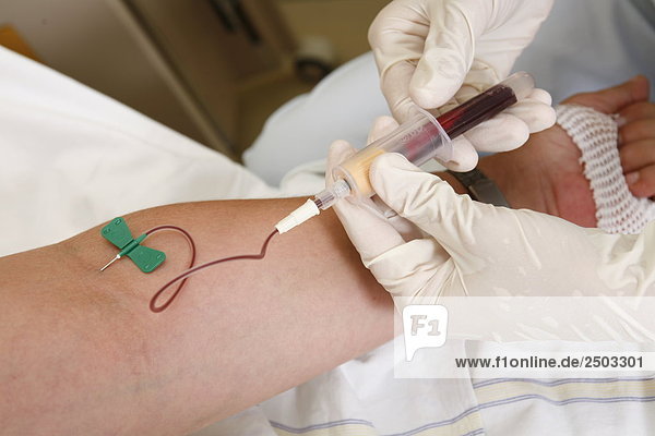 Nahaufnahme der Person Hände nehmen Blutprobe von Arm des Patienten