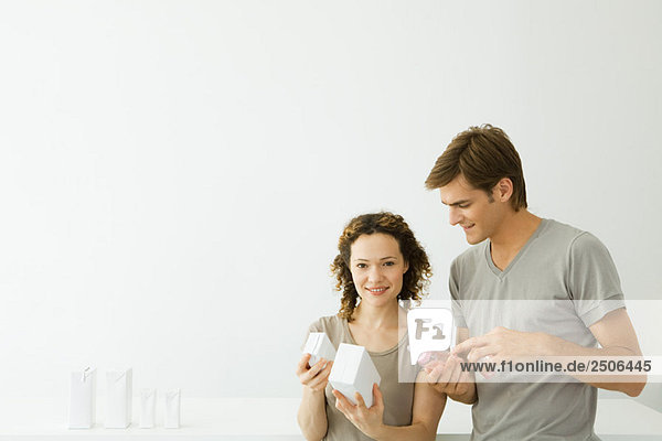 Neue Eltern schauen auf Milchkartons  Mann hält Babyflasche  Frau lächelt in die Kamera