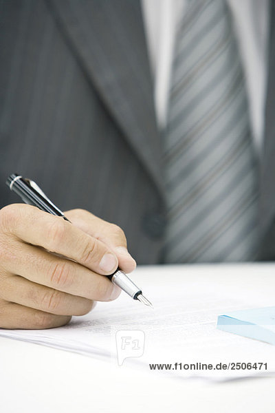 Geschäftsmann beim Schreiben auf dem Dokument  abgeschnittene Ansicht der Hand