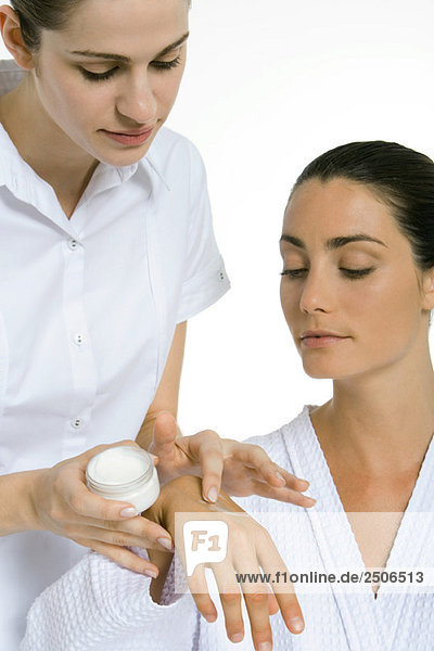 Kosmetikerin beim Auftragen der Feuchtigkeitscreme auf die Hand der Frau