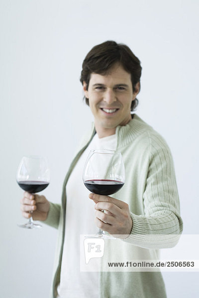 Man holding two glasses of wine  holding out one toward camera