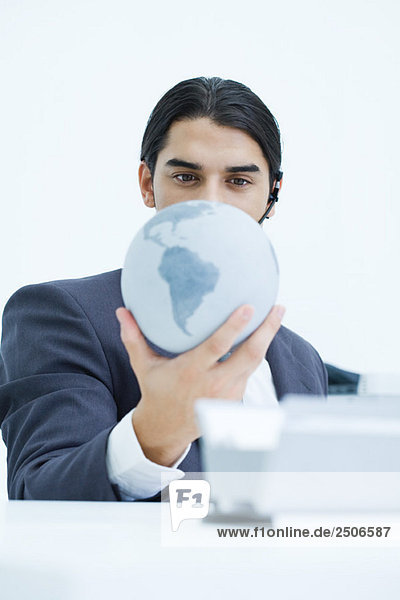 Young businessman holding globe and looking down at it