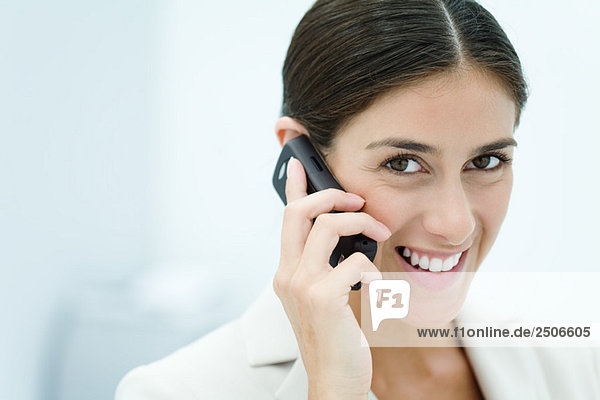 Young woman talking on cell phone  smiling at camera  portrait