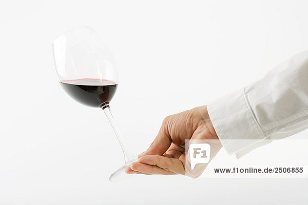 Hand tipping glass of red wine