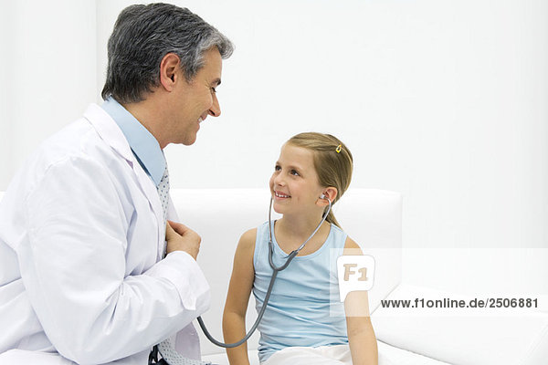 Girl listening to doctor's heart with stethoscope  smiling