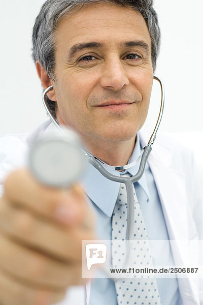 Arzt hält Stethoskop zur Kamera  Fokus auf Hintergrund
