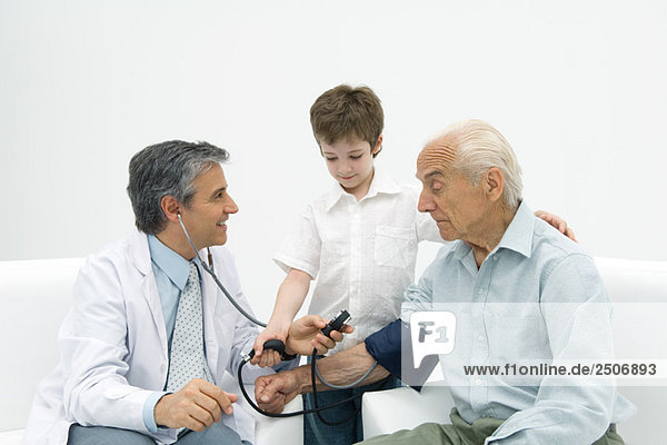 Doctor measuring senior man's blood pressure  boy helping