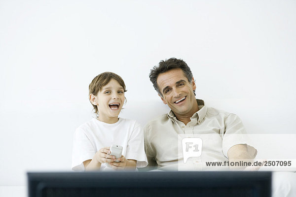 Vater und Sohn schauen zusammen fernsehen  Junge mit Fernbedienung