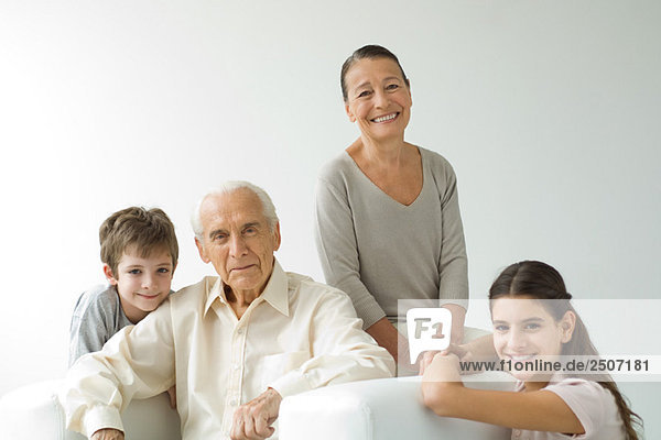 Grandparents sitting with grandchildren  all smiling  portrait