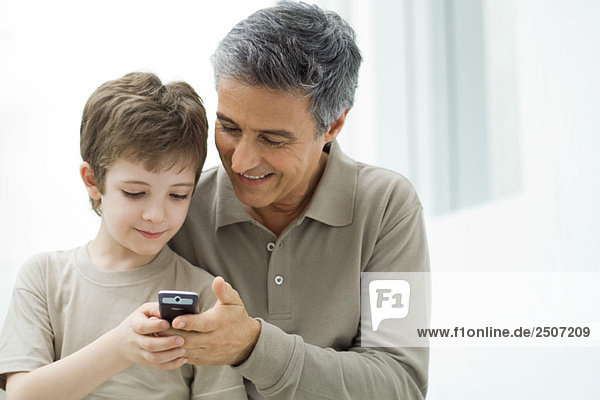 Reifer Mann und junger Sohn schauen gemeinsam auf das Handy