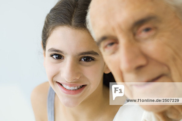 Teenagermädchen schaut Großvater über die Schulter  beide lächelnd  Fokus auf Hintergrund