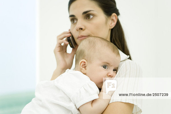 Mother holding infant  using cell phone