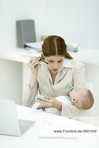 Professionelle Frau im Büro  Wimperntusche auftragend  schlafendes Baby haltend