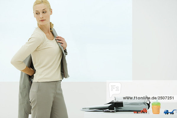 Professionelles Frauen-Dressing  Blick über die Schulter  Trinkbecher und Spielzeug neben der Tasche