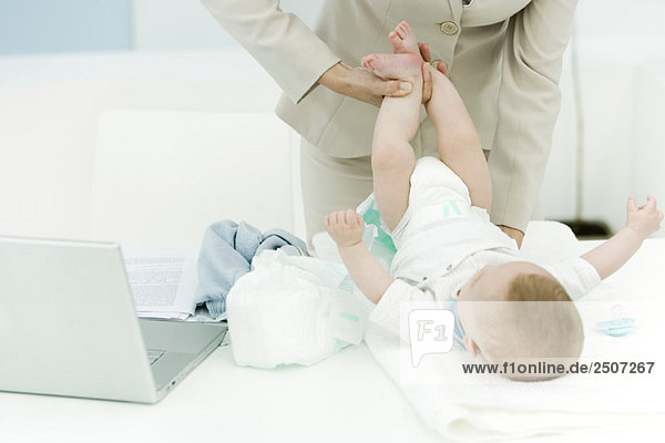 Professionelle Frau beim Wickeln von Babywindeln auf dem Schreibtisch  Schnittansicht