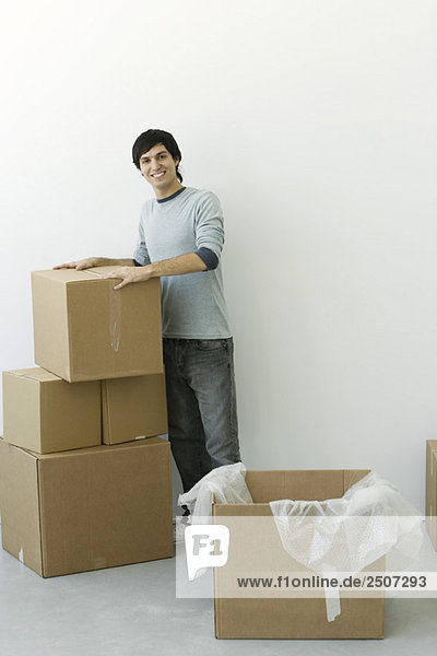 Man standing by stack of cardboard boxes  smiling at camera