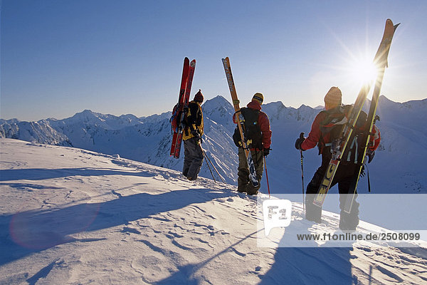 3 Extremskifahrer stehen auf Ridge mit Blick auf Turnagain Arm Chugach CT in South Central Alaska Winter sun