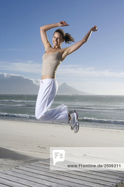 Südafrika  Kapstadt  Junge Frau beim Springen am Strand