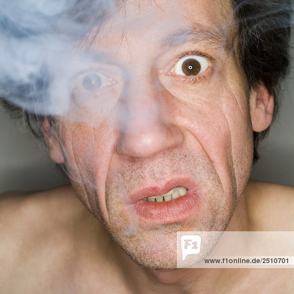 Mann beim Ausatmen von Zigarettenrauch  Nahaufnahme  Portrait