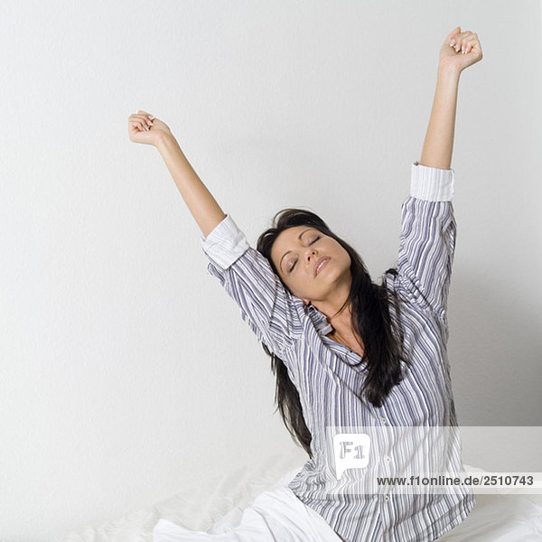 Junge Frau streckt sich im Bett  Porträt