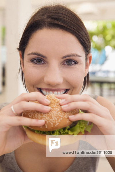 Asia  Thailand  Young woman eating hamburger  smiling  close-up  portrait