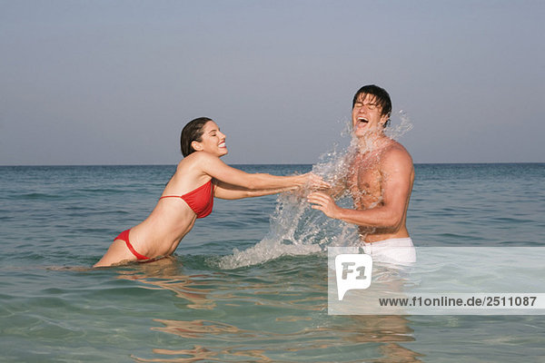 Asia  Thailand  Young Couple in ocean  splashing water