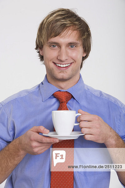 Junger Mann hält Tasse Kaffee  Porträt