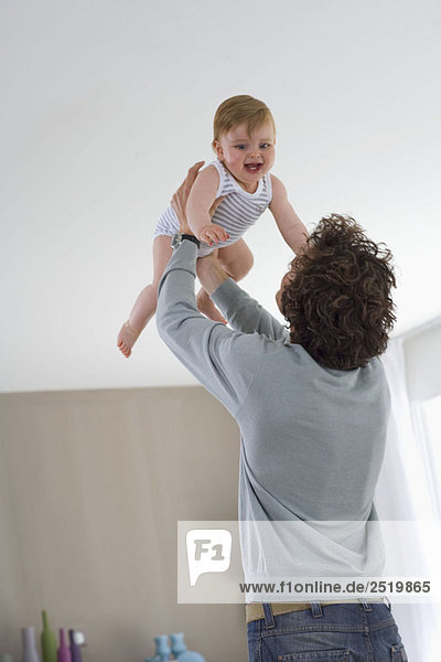 Vater hält glückliches Baby in der Luft im Haus