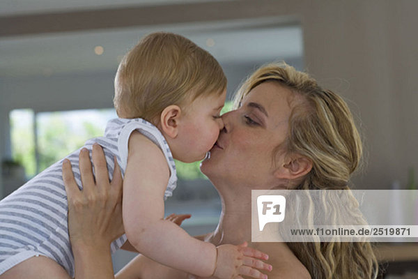 Mutter küsst Baby auf den Mund zu Hause