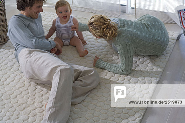 Eltern spielen mit Baby auf dem Teppich