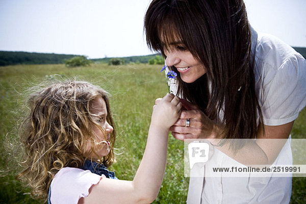 Frau riecht Blume mit Tochter