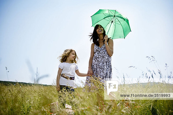 Frau mit Tochter hält Regenschirm