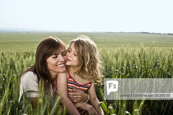 Kind küssende Mutter im Weizenfeld