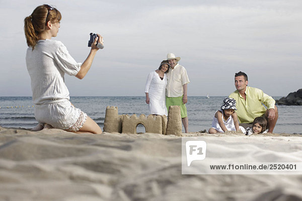 Mother taking video of family on beach