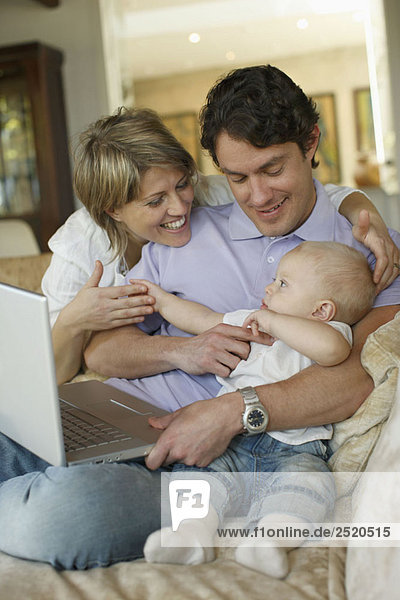 Young family on sofa with laptop