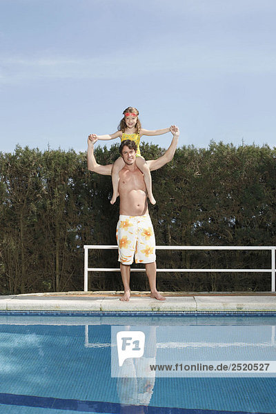 Vater trägt Mädchen am Pool