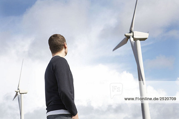 Mann schaut auf Windkraftanlagen