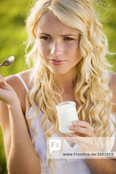 Porträt einer jungen Frau beim Joghurtessen