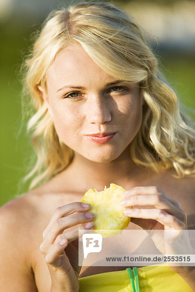 Junge Frau beim Essen einer Ananasscheibe