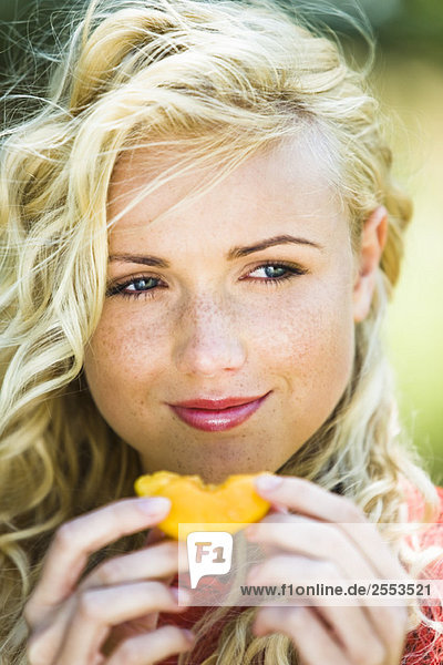 Junge Frau beim Essen einer gelben Tomate