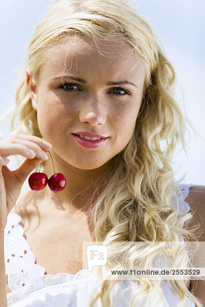 Young woman holding two cherries