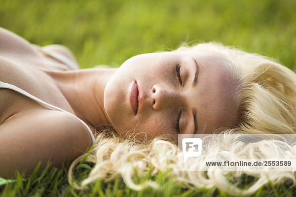 Junge Frau schläft im Gras